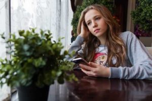 girl with phone looking sad